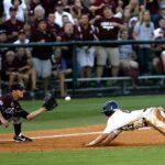 Dramatic moment as a baseball player slides home during a lively game amidst cheering crowd.