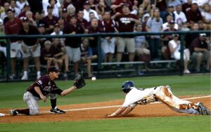 Dramatic moment as a baseball player slides home during a lively game amidst cheering crowd.