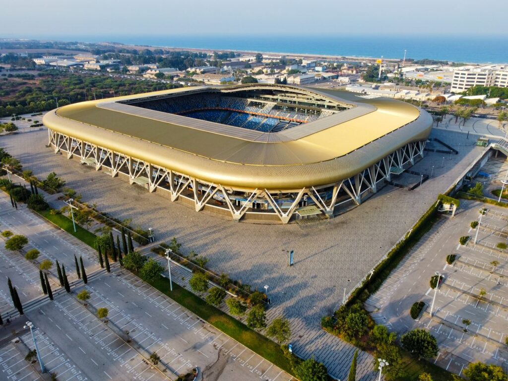Aerial view of a modern stadium in an urban area, showcasing its unique architecture and surroundings.